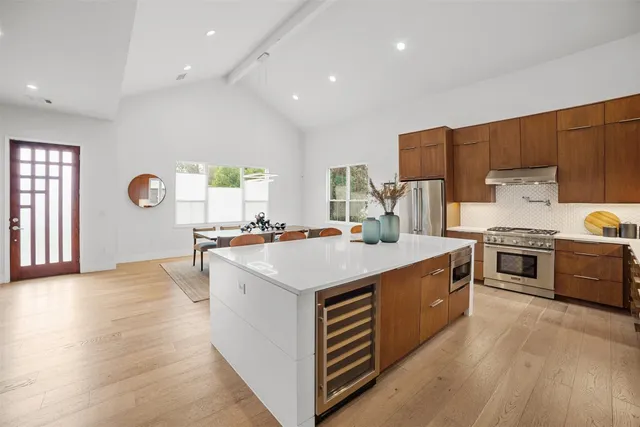 a kitchen with kitchen island a sink dishwasher stove and white cabinets with wooden floor