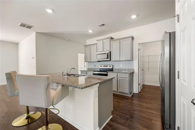a kitchen with kitchen island granite countertop a sink cabinets and wooden floor