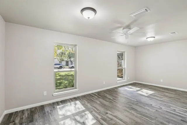 a view of empty room with wooden floor and fan