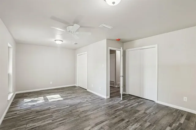an empty room with wooden floor and ceiling fan
