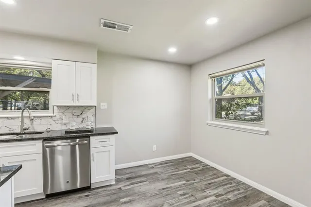 a kitchen with stainless steel appliances granite countertop a sink and dishwasher with wooden floor