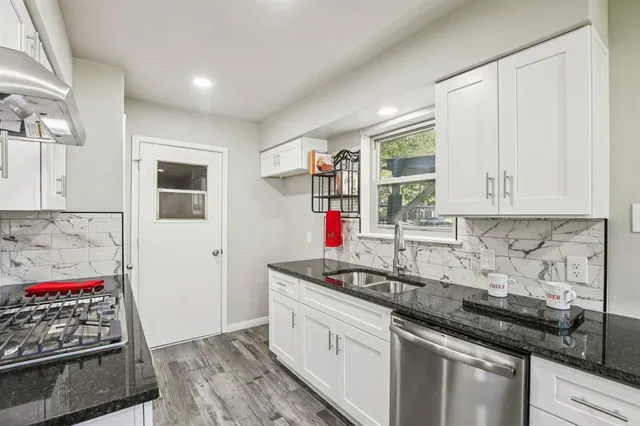 a kitchen with stainless steel appliances granite countertop a sink stove and cabinets