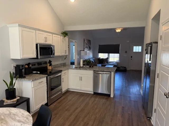 a kitchen with granite countertop a refrigerator stove and sink