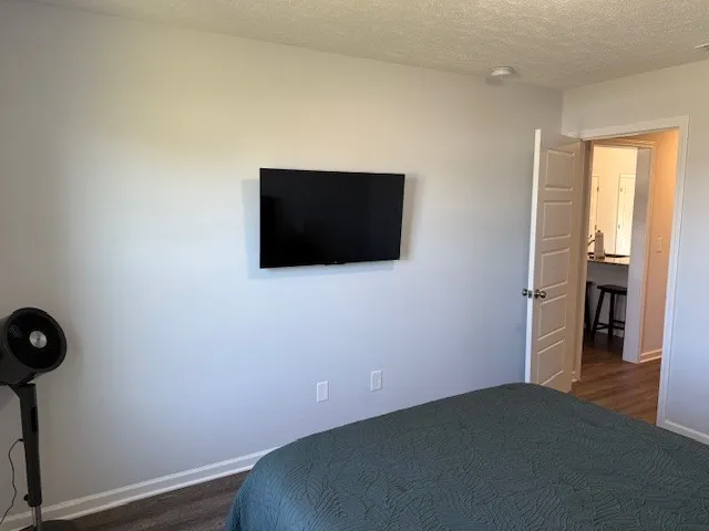 a view of a hallway with wooden floor and a bathroom
