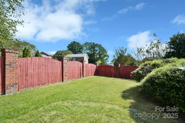 a view of a backyard with flower plants and wooden fence