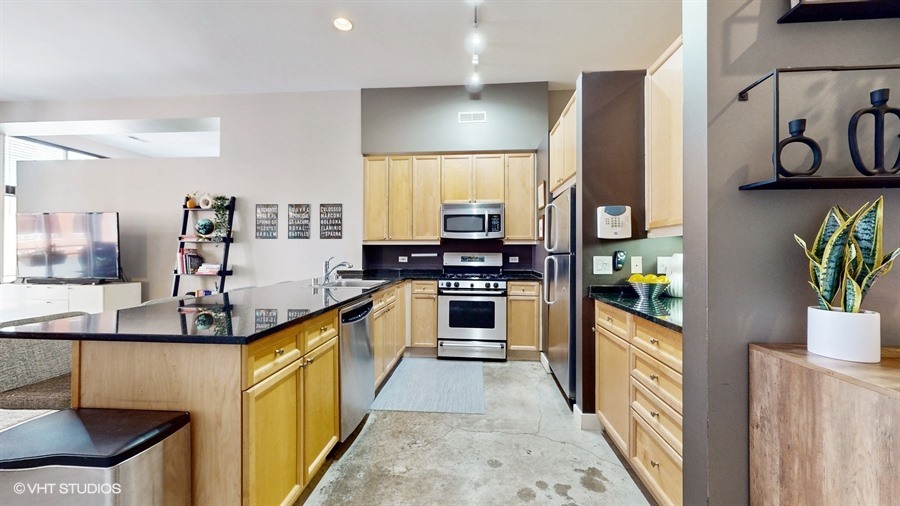 949 West Madison Street, Unit 401 Chicago, IL 60607 - Photo 6 of 14 a kitchen with stainless steel appliances kitchen island granite countertop a stove a sink and a refrigerator