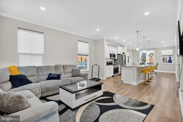 a living room with furniture and kitchen view with wooden floor