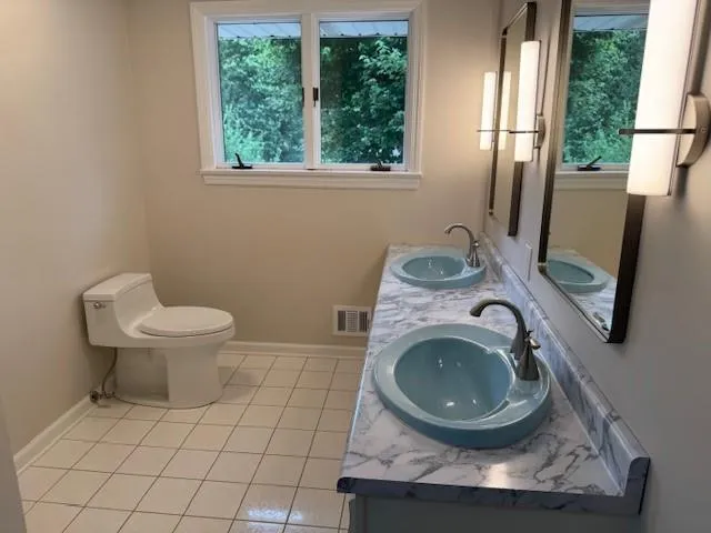 a bathroom with a granite countertop toilet sink and mirror
