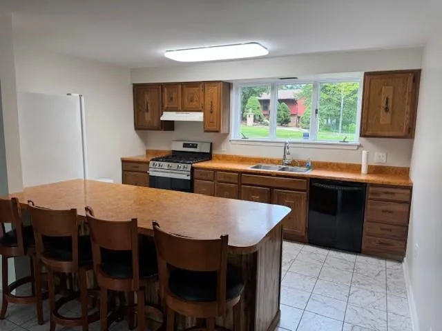 a kitchen with stainless steel appliances granite countertop a stove a refrigerator a sink a dining table and chairs