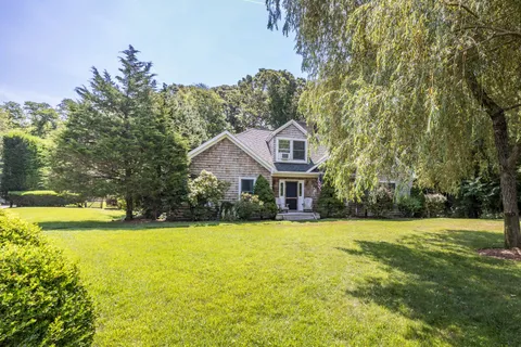 a view of a house with a big yard and large trees