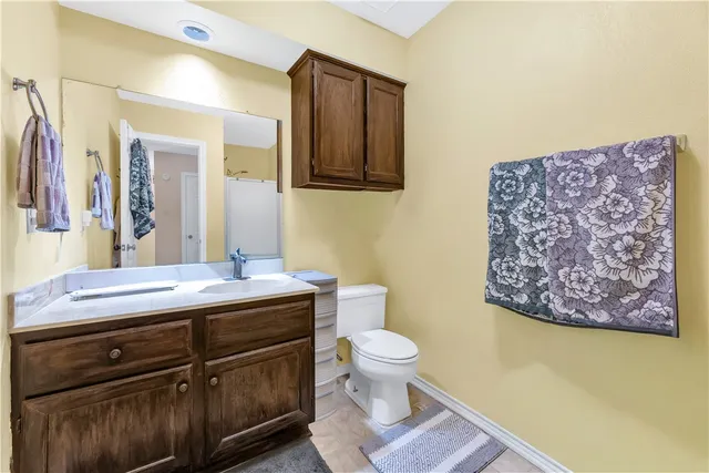 a bathroom with a granite countertop toilet sink and mirror