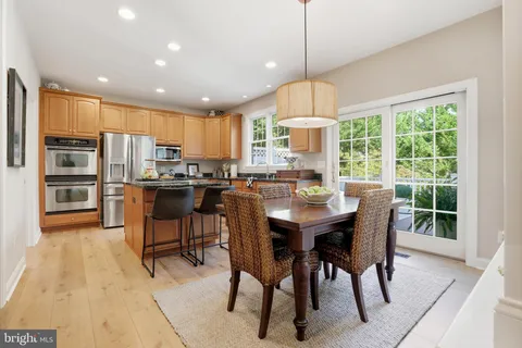 a open kitchen with stainless steel appliances granite countertop wooden floor dining table and chairs