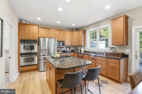 a kitchen with stainless steel appliances granite countertop a table chairs sink refrigerator and cabinets