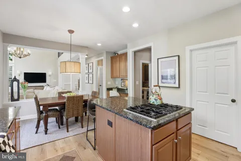a kitchen with granite countertop a stove a sink dishwasher a dining table and chairs with wooden floor