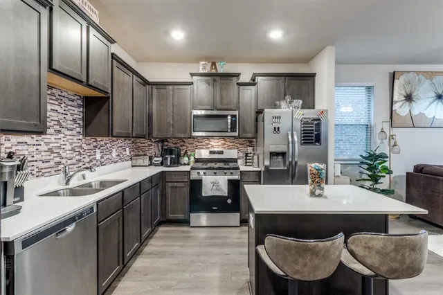 a kitchen with granite countertop a sink stainless steel appliances and cabinets