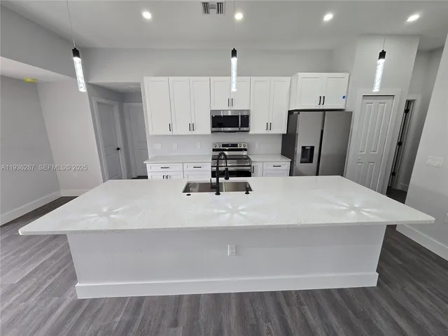 a large white kitchen with wooden floor