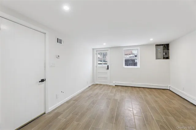 a view of an empty room with wooden floor and a window