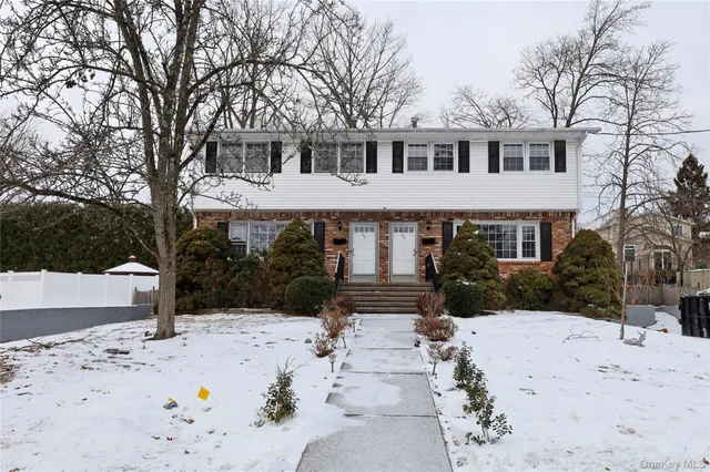 a front view of a house with a yard covered in snow