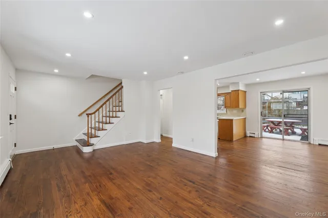 a view of an empty room with wooden floor and a ceiling fan
