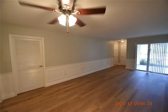 an empty room with wooden floor fan and windows