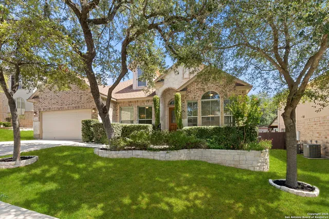 a front view of a house with a yard and tree