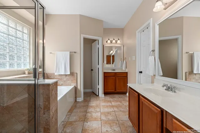 a bathroom with a double vanity sink a mirror and a bathtub