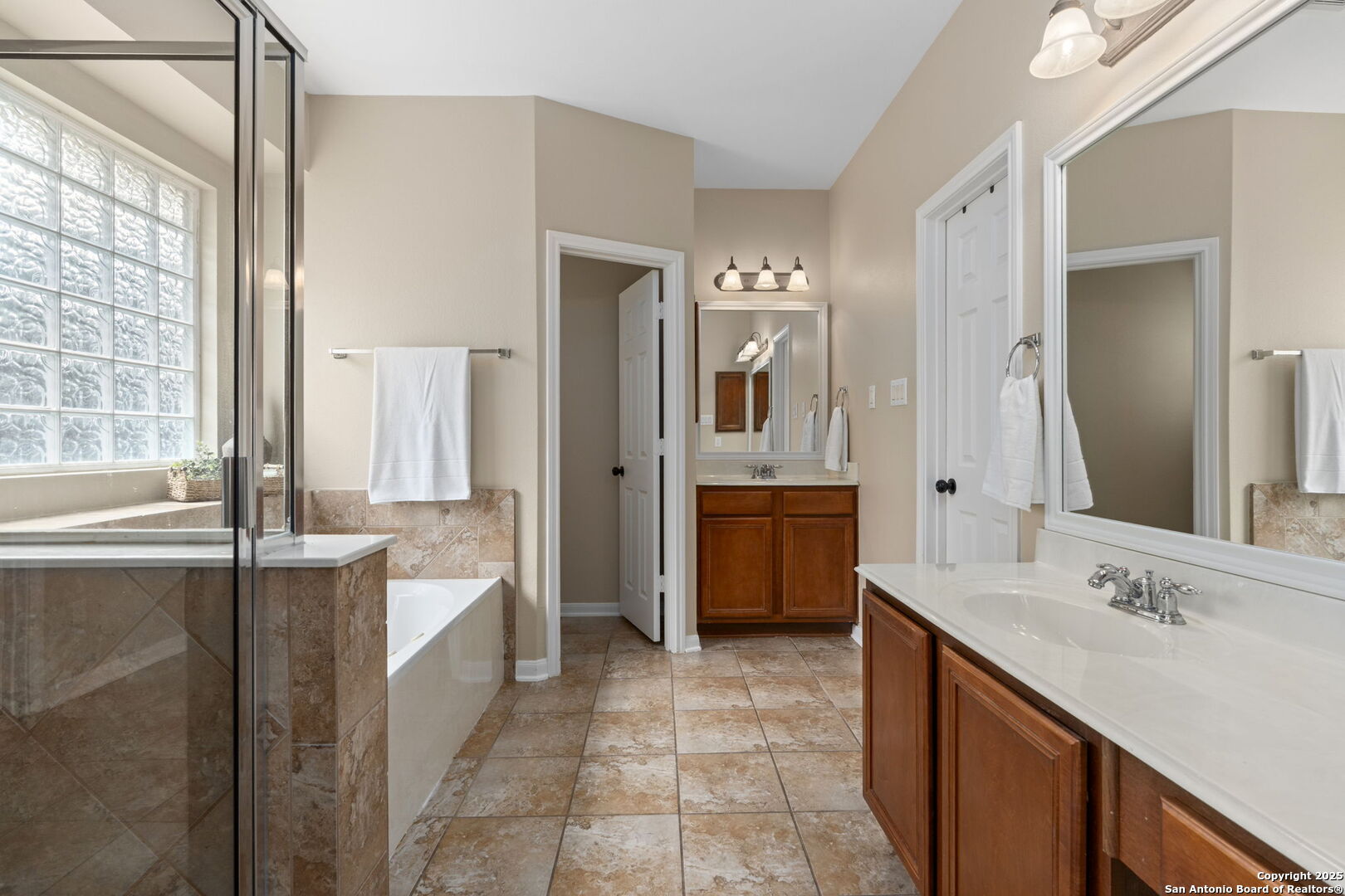 16106 Ponderosa Pth Helotes, TX 78023 - Photo 26 of 40 a bathroom with a double vanity sink a mirror and a bathtub