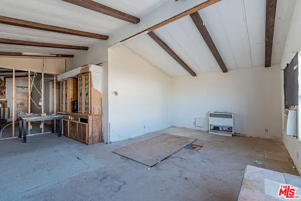 a view of an empty room with furniture and windows