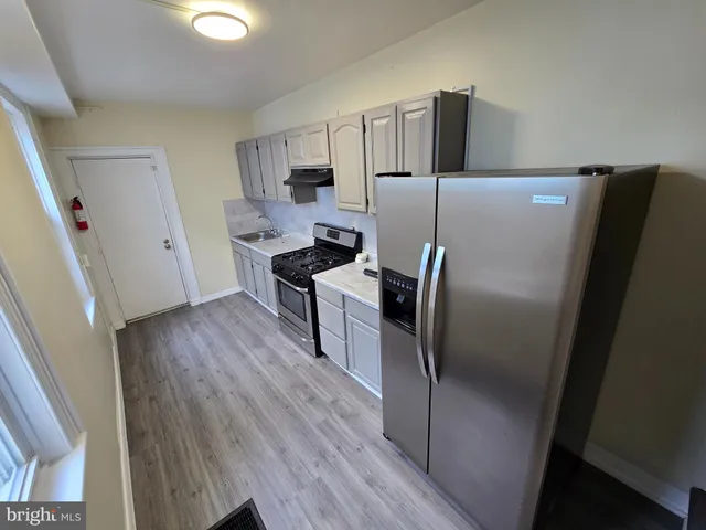 a kitchen with a refrigerator sink and wooden floor