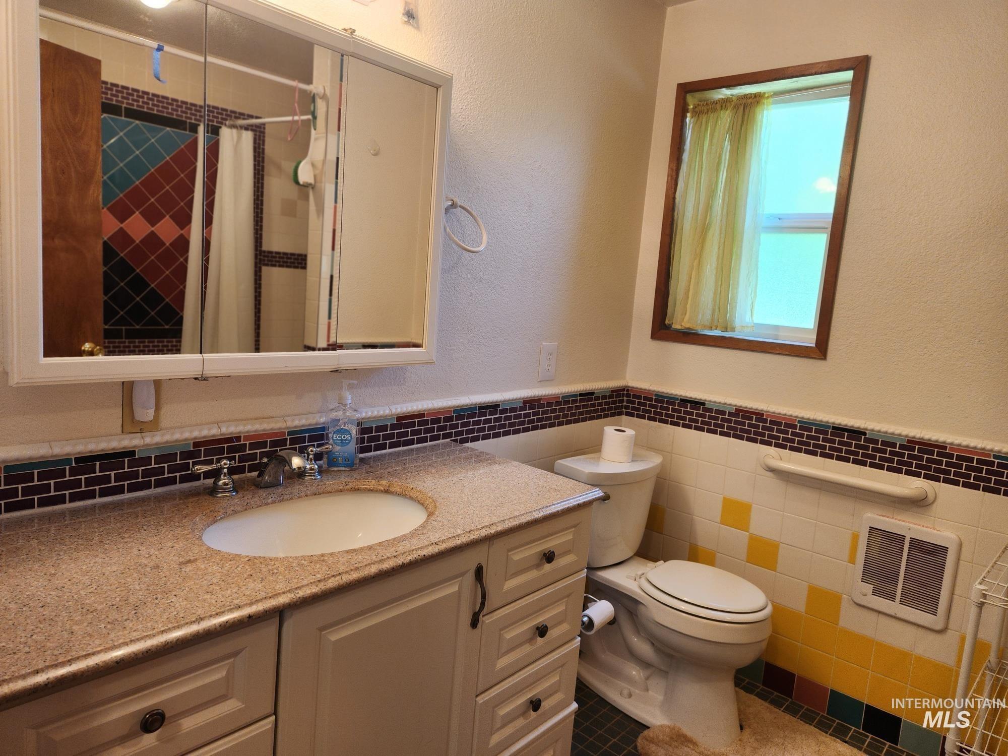 367 Woodland Road Kamiah, ID 83536 - Photo 32 of 45 Full bathroom featuring a textured wall, vanity, a tile shower, tile walls, and wainscoting
