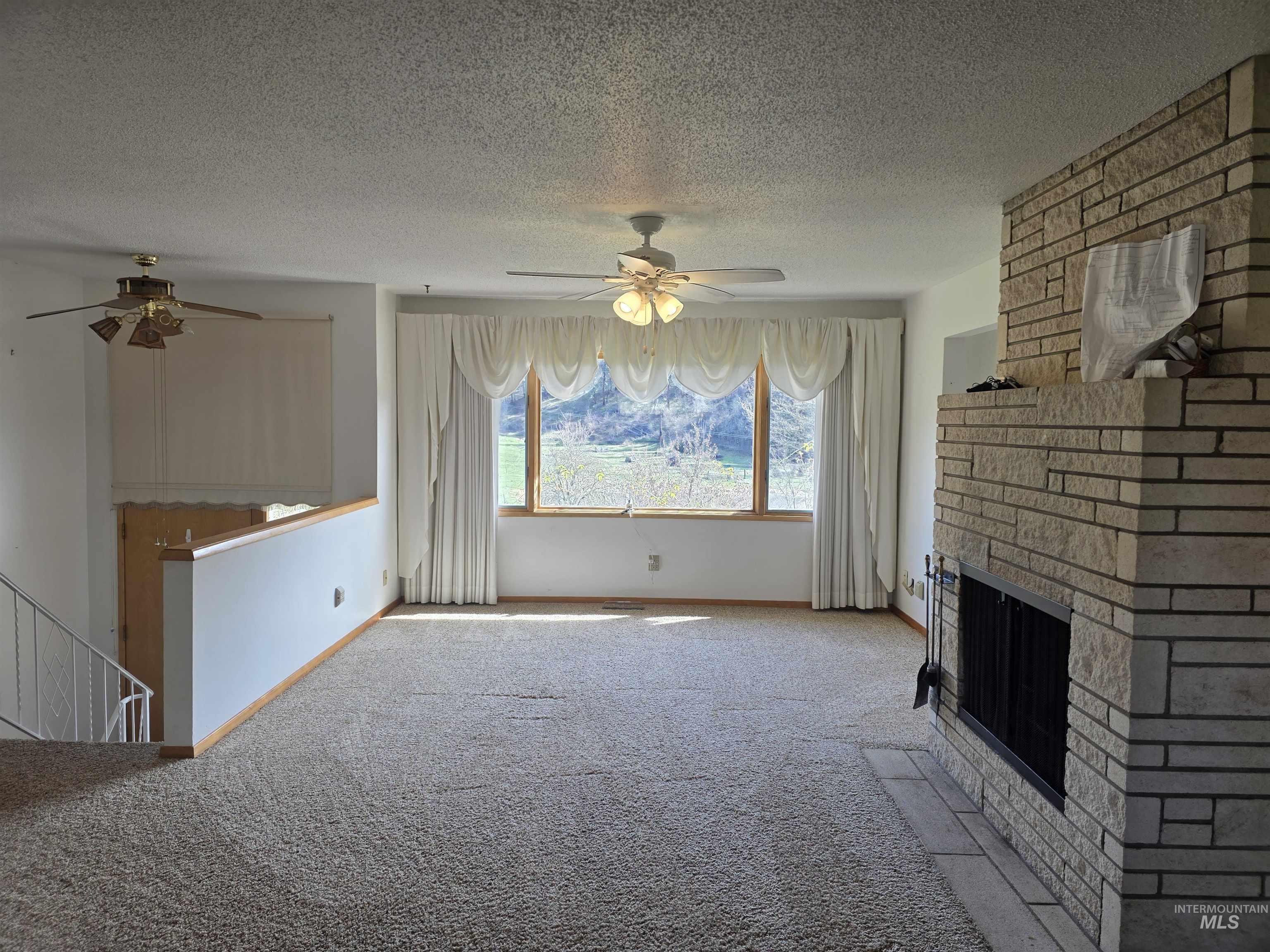 367 Woodland Road Kamiah, ID 83536 - Photo 5 of 45 Unfurnished living room featuring ceiling fan, carpet floors, a textured ceiling, and a fireplace