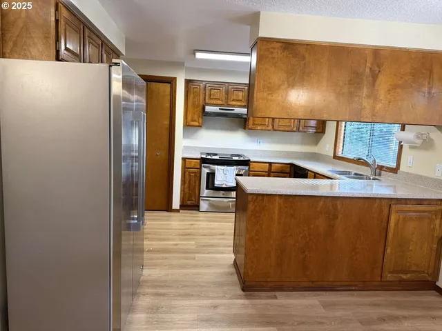 a kitchen with stainless steel appliances granite countertop a refrigerator a stove and a sink