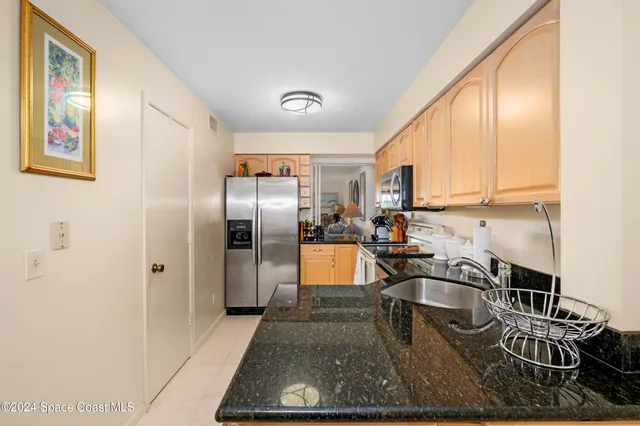 a kitchen with stainless steel appliances granite countertop a refrigerator a stove and a sink with wooden floor