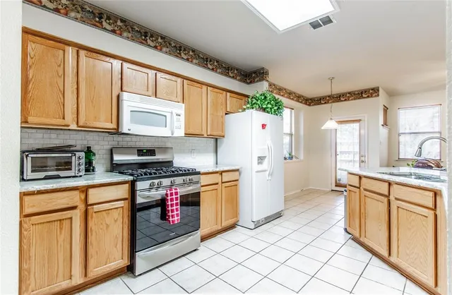 a kitchen with stainless steel appliances granite countertop a stove a sink and a refrigerator