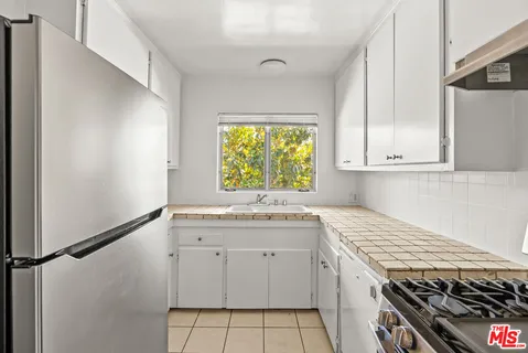 a kitchen with white cabinets appliances and a window