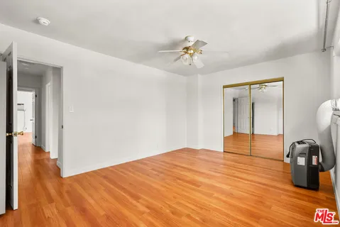 a view of an empty room with chandelier fan and wooden floor