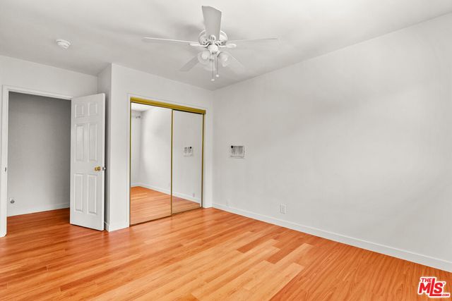 a view of empty room with wooden floor and ceiling fan