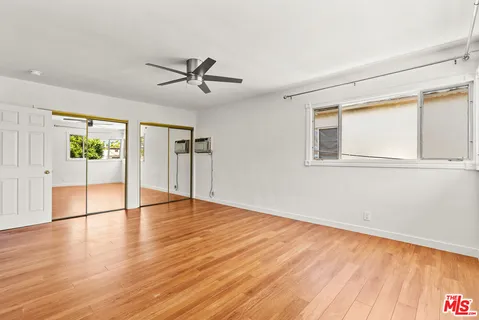 a view of empty room with wooden floor and fan