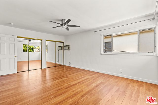 a view of empty room with wooden floor and fan