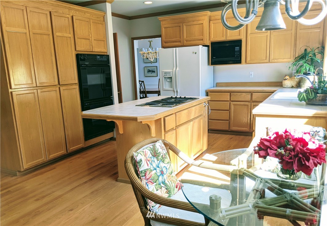 3016 214th Street Southeast Bothell, WA 98021 - Photo 6 of 25 a kitchen with stainless steel appliances kitchen island granite countertop a refrigerator a stove a sink and white cabinets with wooden floor