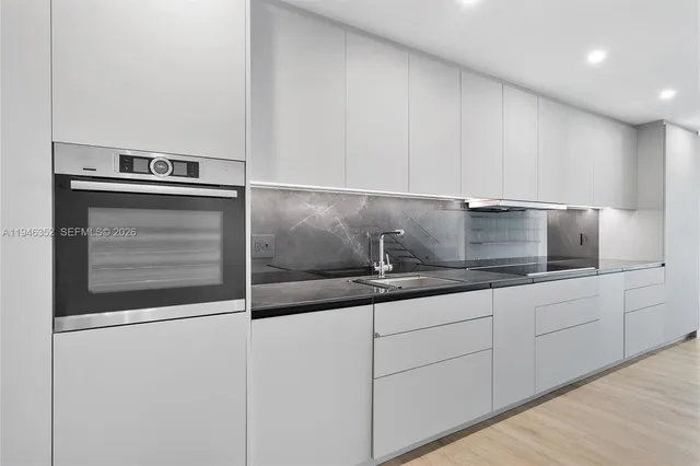 a kitchen with granite countertop white cabinets and stainless steel appliances