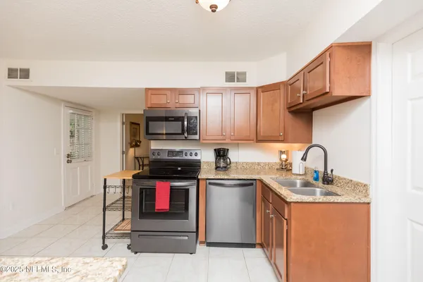 a kitchen with stainless steel appliances granite countertop a stove top oven a sink dishwasher and white cabinets with wooden floor