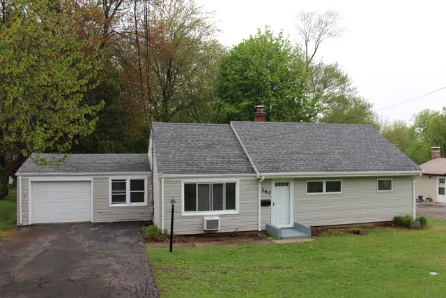 a view of a yard in front of a house with plants and large tree