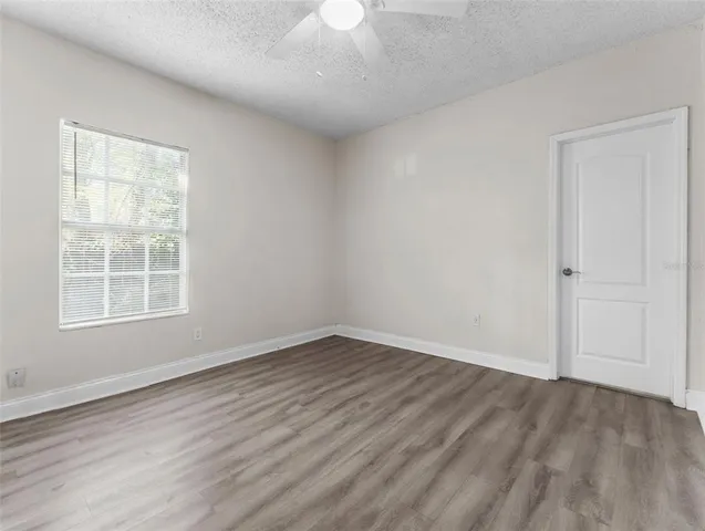 an empty room with wooden floor cabinet and windows