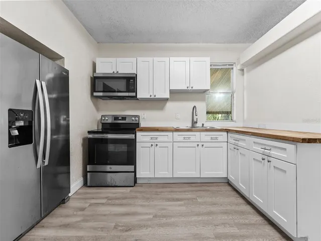 a kitchen with granite countertop a refrigerator stove and microwave