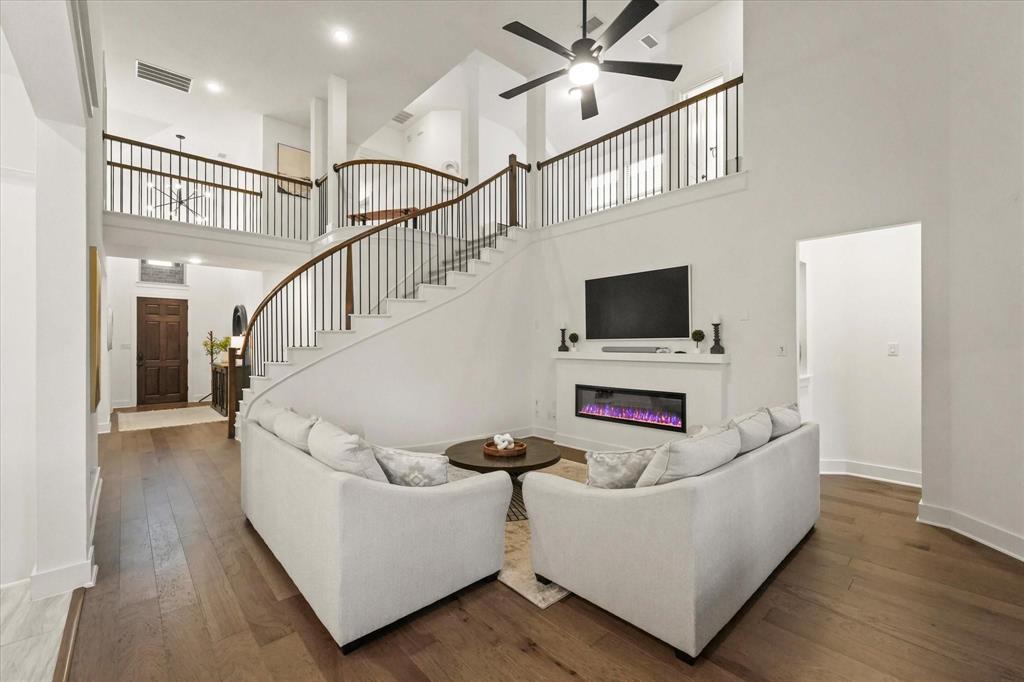 1714 Highwood Road Forney, TX 75126 - Photo 8 of 28 Living area featuring a glass covered fireplace, dark wood-style flooring, ceiling fan, and a high ceiling