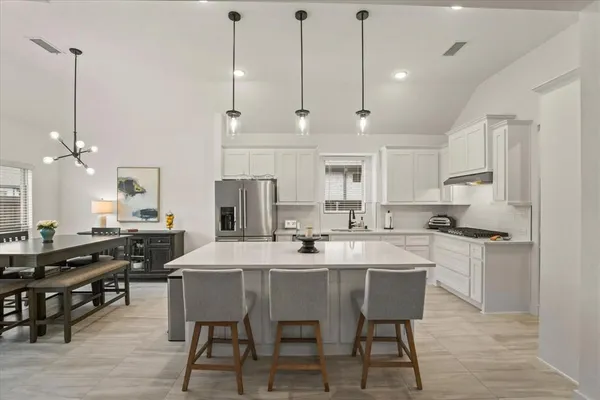 a kitchen with stainless steel appliances kitchen island granite countertop a table chairs sink and cabinets