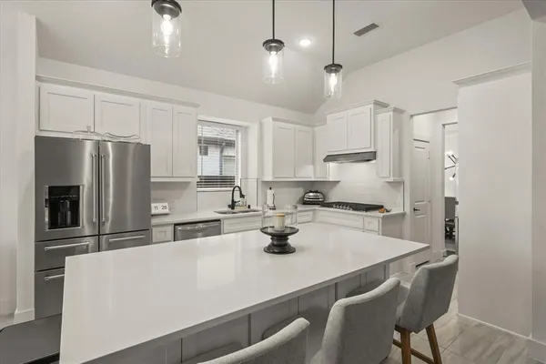 a kitchen with refrigerator a stove a sink and chairs