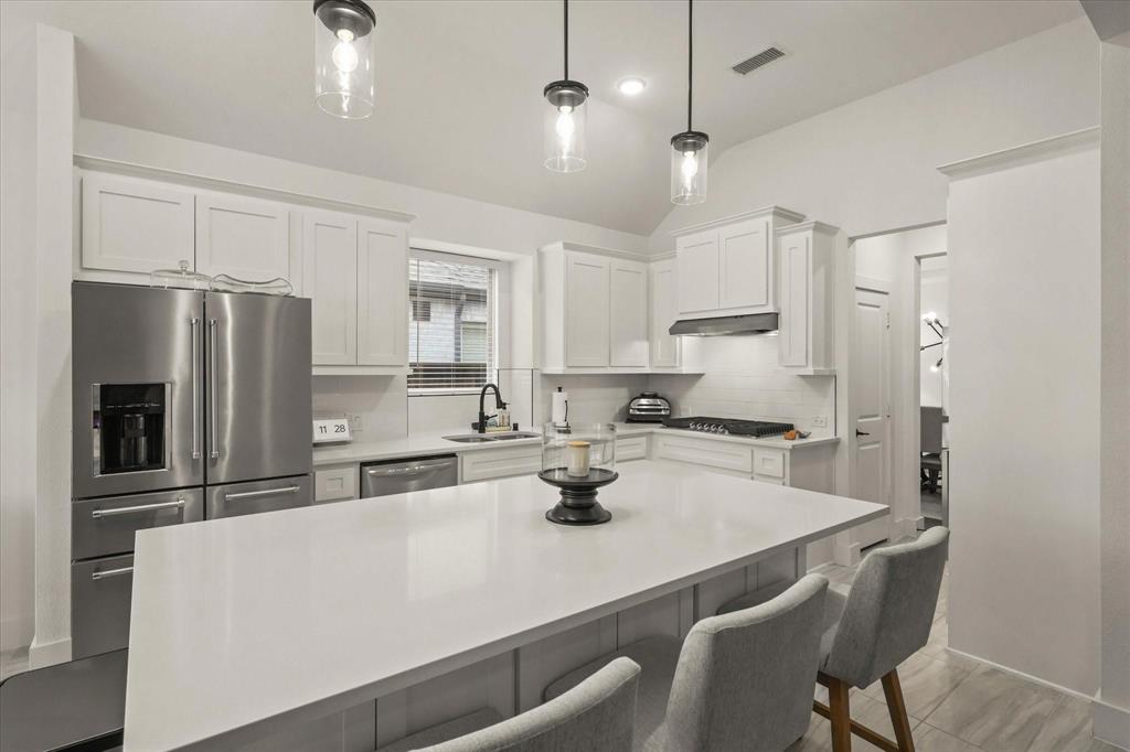 1714 Highwood Road Forney, TX 75126 - Photo 10 of 28 Kitchen with stainless steel appliances, white cabinetry, a kitchen bar, decorative light fixtures, and lofted ceiling