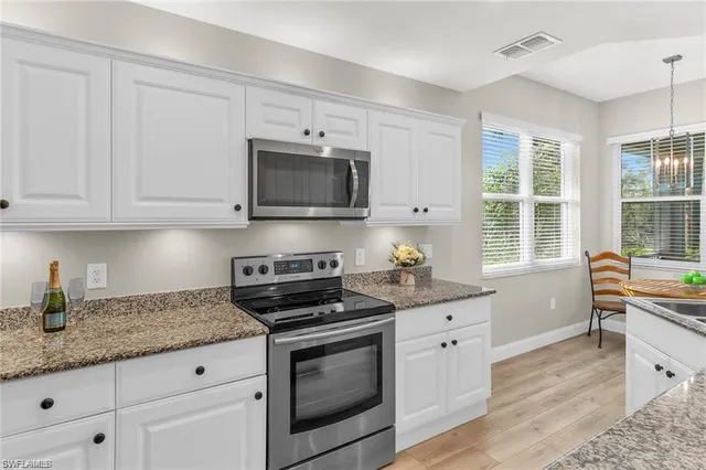 a kitchen with granite countertop a stove a sink and a microwave
